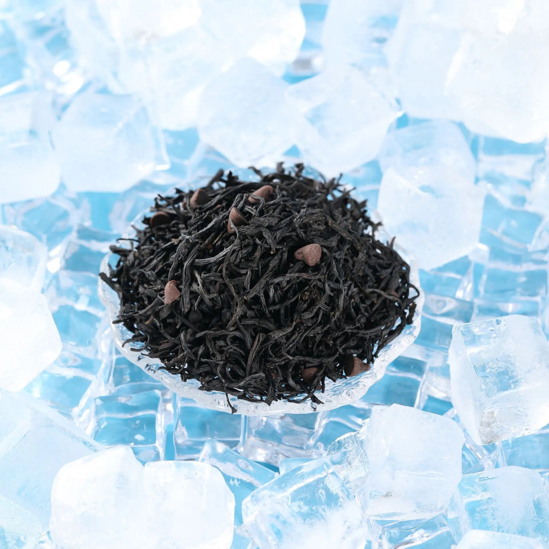 A cold brew tea glass on ice cubes with pu-erh tea leaves and coffee beans in the background.