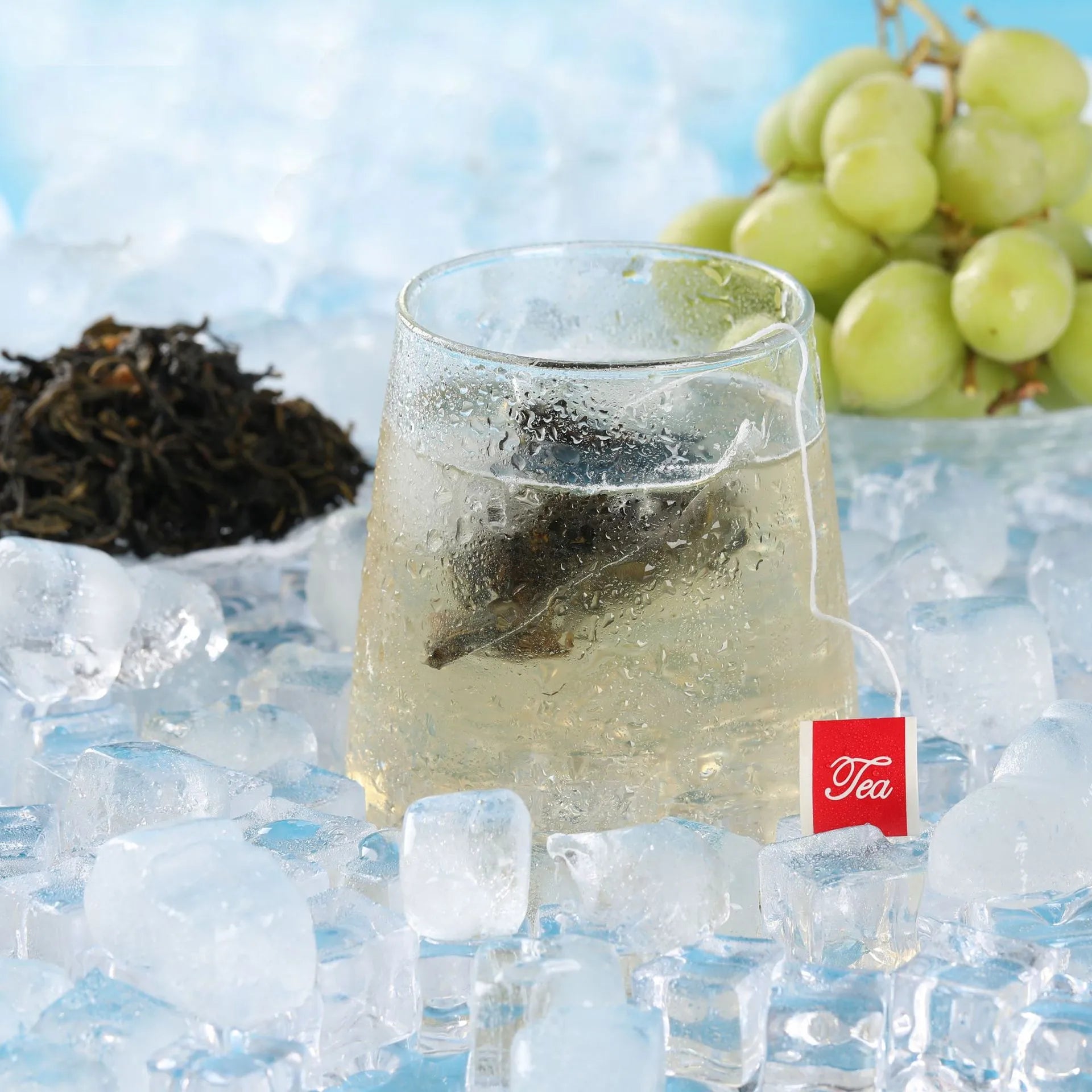 Chilled glass of grape oolong cold brew tea with condensation, grapes in the background