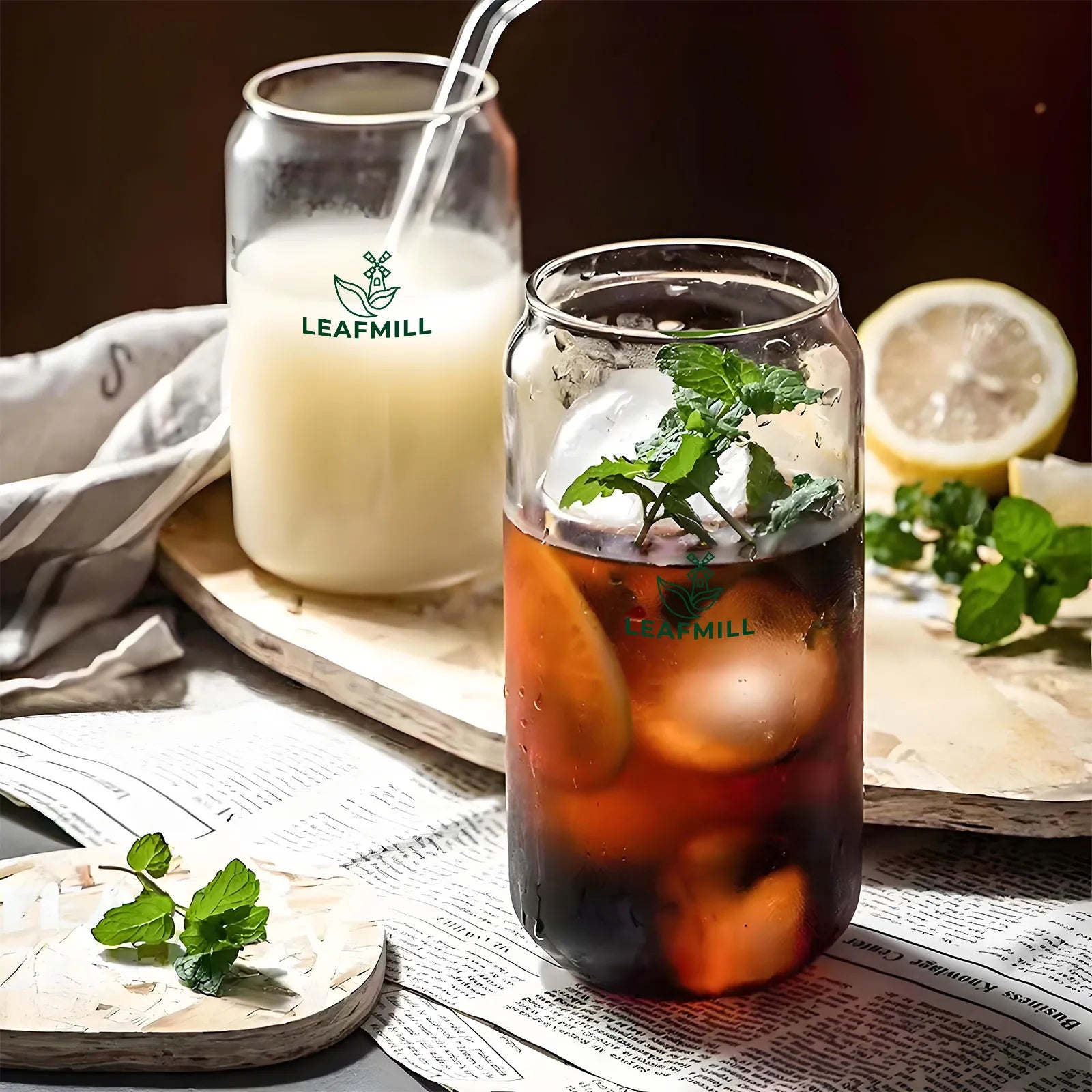 Leafmill 500ml borosilicate glass cups with logo, filled with iced tea and milk tea, served with lemon and mint on a wooden tray