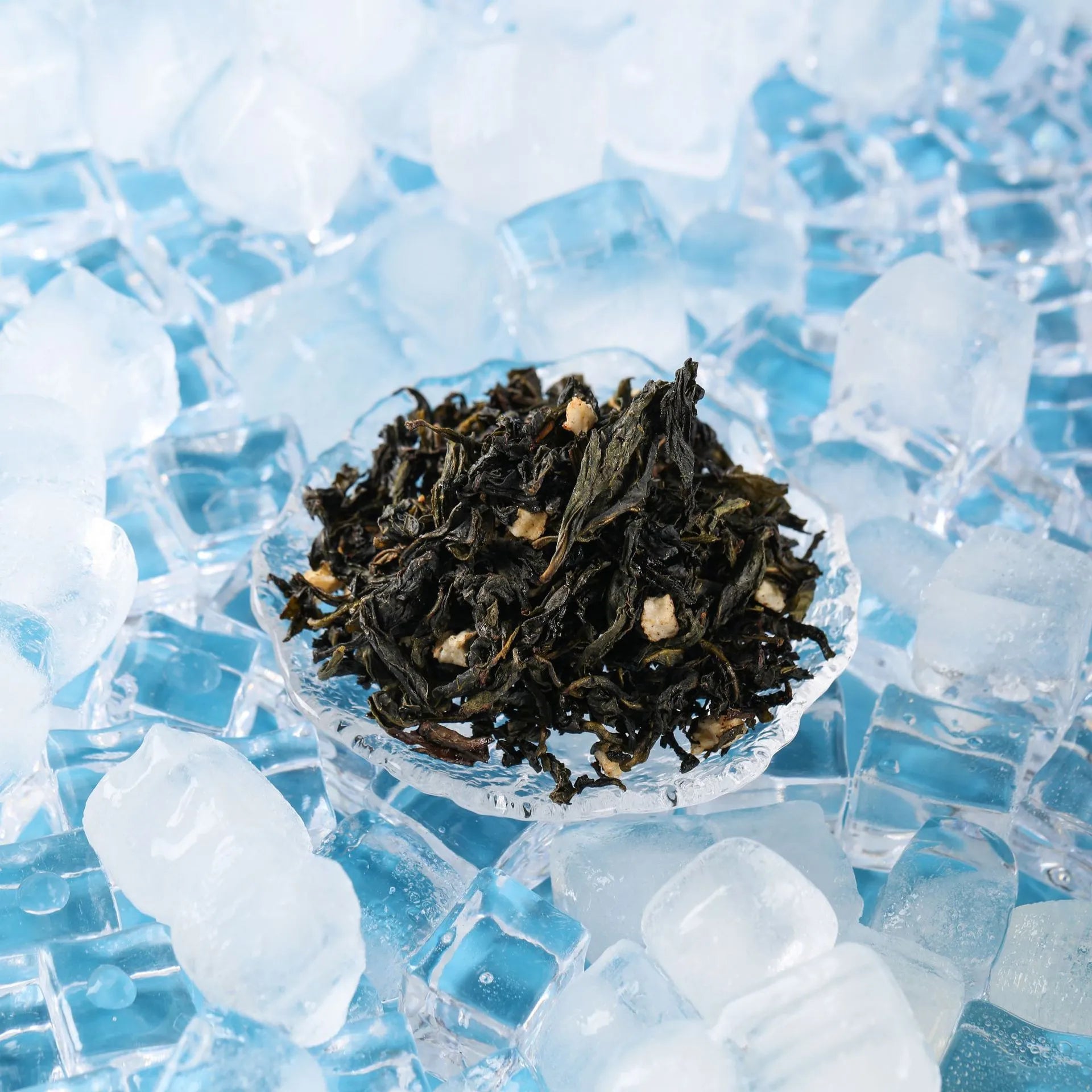 Loose passion fruit oolong tea leaves displayed on a glass dish over ice cubes, highlighting freshness and ingredients.