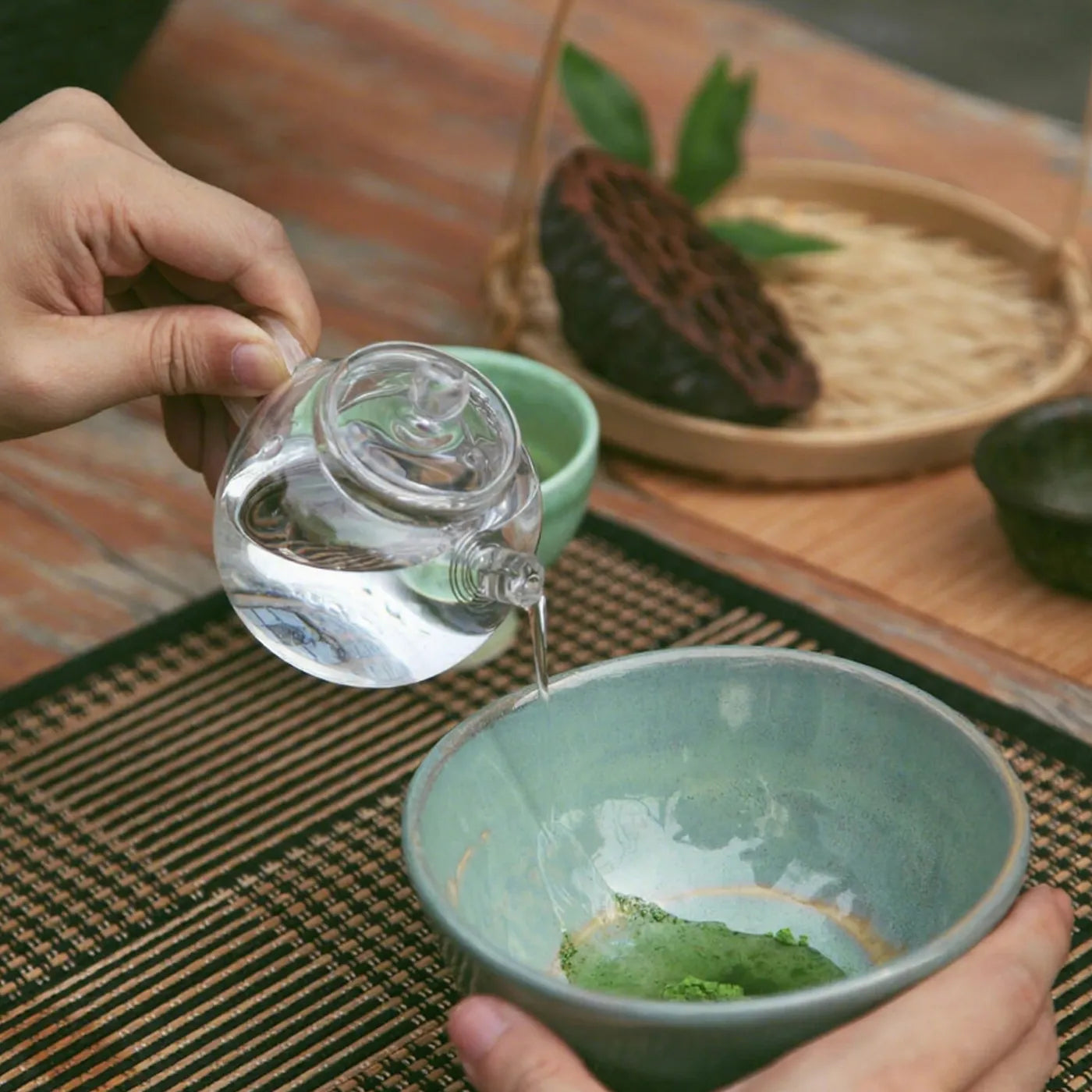 Step two of traditional matcha preparation – pouring hot water over ceremonial-grade matcha powder in a chawan tea bowl