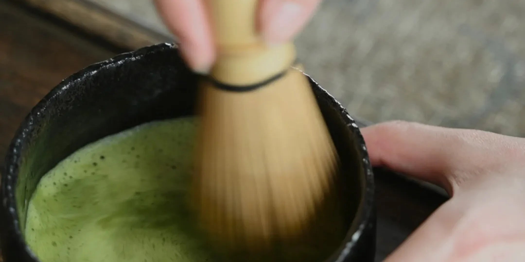 Hero banner showing bamboo whisk frothing vibrant green matcha tea in a traditional black bowl – Leafmill matcha preparation
