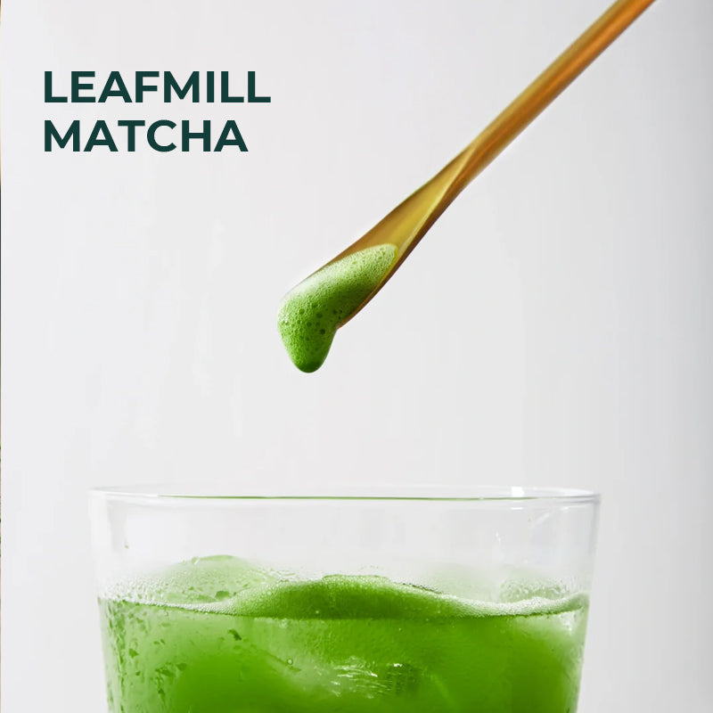 Close-up of Leafmill iced matcha drink with foam on bamboo spoon – premium green tea experience in glass cup