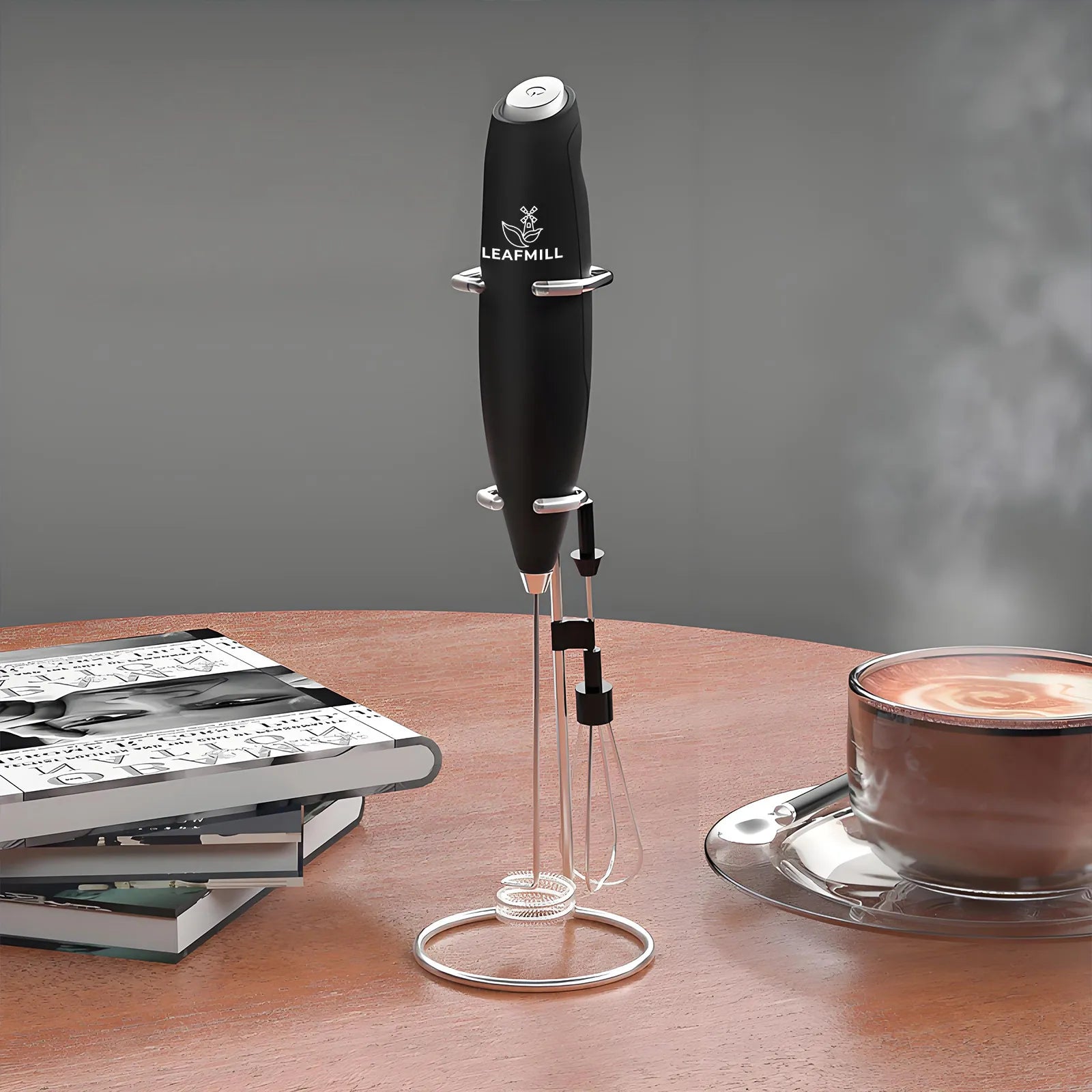 Leafmill electric matcha frother standing on a wooden table beside coffee and books