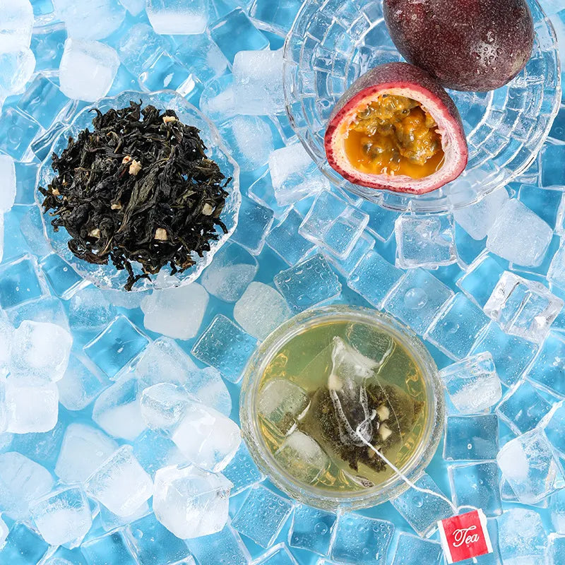 Flat lay of passion fruit oolong cold brew tea, featuring a glass with a tea bag, passion fruit, and loose tea leaves on ice.